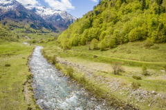 Une rivière en montagne en vallée d'Ossau au printemps avec les montagnes enneigées (vue aérienne)//A mountain river in the Ossau valley in spring with the snow-capped mountains (aerial view)